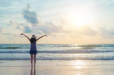 a woman standing on the beach with her arms outstretched at cottage near the beach in the center.**** in Noordwijk aan Zee