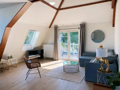 a living room with a blue couch and a table at Luxurious historical Loft close to the beach! in Wassenaar