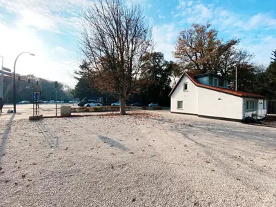an empty parking lot with a white building and a tree at Luxurious historical Loft close to the beach! in Wassenaar