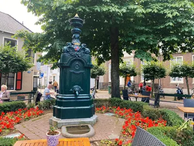 a green statue in the middle of a park with flowers at Luxurious historical Loft close to the beach! in Wassenaar
