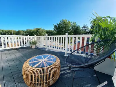 a wicker chair and a bench on a deck at Luxurious historical Loft close to the beach! in Wassenaar