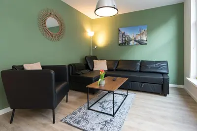 a living room with a black couch and a table at Alkmaar City Apartments in Alkmaar