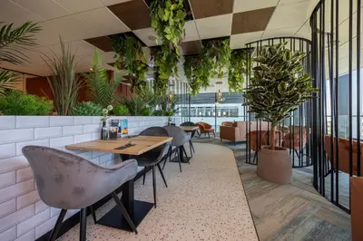 a restaurant with tables and chairs and plants at Fletcher Wellness-Hotel Leiden in Leiden