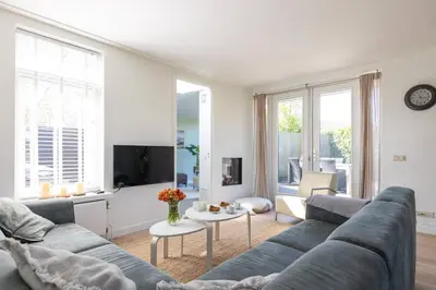 a living room with a blue couch and a tv at Kustlijn vakantiewoning in Egmond aan den Hoef