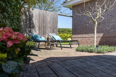 two chairs sitting on a patio in a yard at Kustlijn vakantiewoning in Egmond aan den Hoef