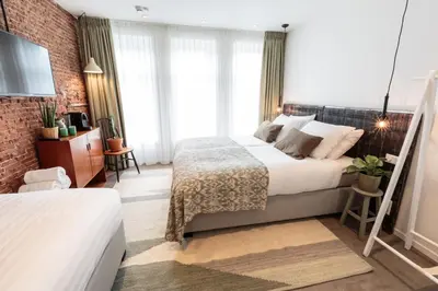 a bedroom with two beds and a brick wall at Hotel Dwars in Amsterdam