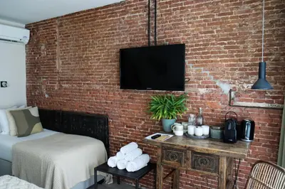 a bedroom with a brick wall with a tv on a wall at Hotel Dwars in Amsterdam