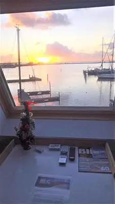 a window with a view of a harbor with a sunset at Kaap Hoorn Club Bed en Breakfast in Hoorn