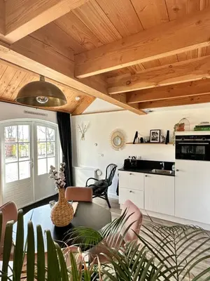 a kitchen and living room with wooden ceilings and a table at Noxem b&b in Boesingheliede