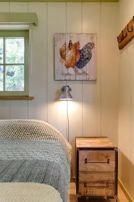 a bedroom with a bed and a chicken painting on the wall at Cottage 'Onder de boompjes' in Oostwoud