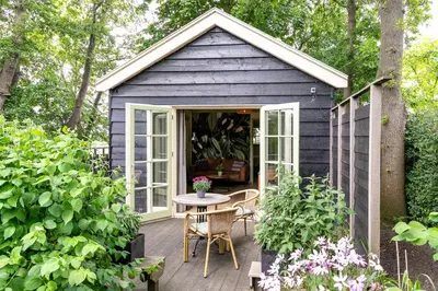 a blue shed with a table and chairs on a deck at Cottage 'Onder de boompjes' in Oostwoud