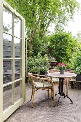 a patio with a table and a chair and a window at Cottage 'Onder de boompjes' in Oostwoud