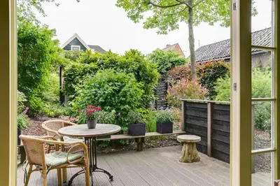 a patio with a table and chairs and a garden at Cottage 'Onder de boompjes' in Oostwoud