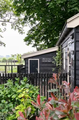 a black building with a sign in front of it at Cottage 'Onder de boompjes' in Oostwoud