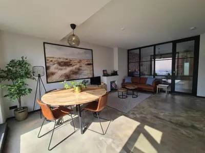 a living room with a wooden table and chairs at De Boulevard 2 in Zandvoort