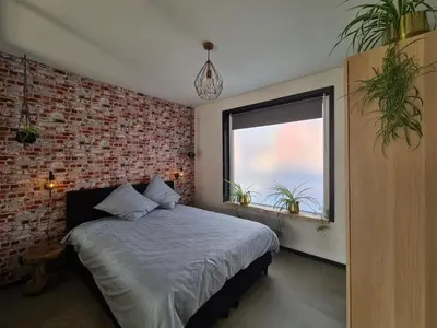 a bedroom with a bed and a brick wall at De Boulevard 2 in Zandvoort