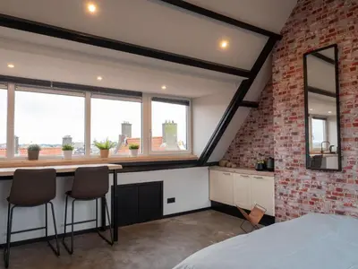 a loft conversion bedroom with a brick wall and a desk at De Boulevard 2 in Zandvoort