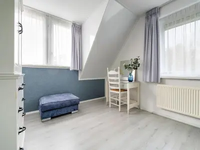 a attic room with a blue ottoman and windows at Holiday Home in Zeewolde near Forest in Zeewolde