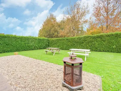 a park with two picnic tables in the grass at Holiday Home in Zeewolde near Forest in Zeewolde