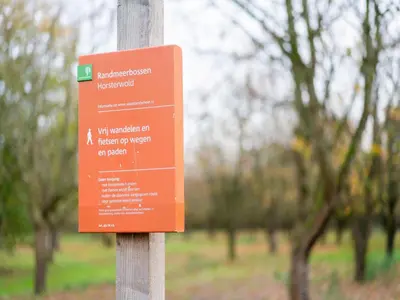 an orange sign on a pole in a park at Holiday Home in Zeewolde near Forest in Zeewolde