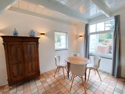 a dining room with a table and chairs and a window at Cozy historical Cottage (Huisje HèHè) in Wassenaar