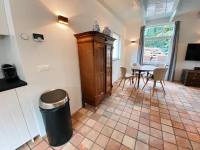 a room with a table and a wooden cabinet at Cozy historical Cottage (Huisje HèHè) in Wassenaar