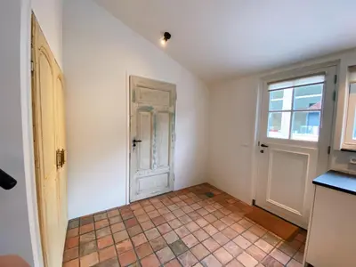 an empty room with a door and a tile floor at Cozy historical Cottage (Huisje HèHè) in Wassenaar