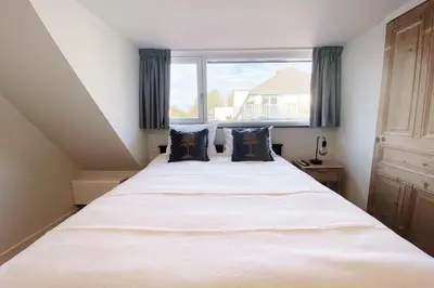 a bedroom with a large white bed with a window at Cozy historical Cottage (Huisje HèHè) in Wassenaar