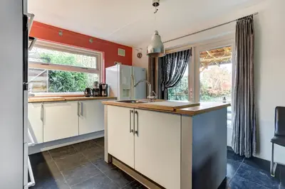 a kitchen with white cabinets and a sink at Villa Leeuwerik (4-12 p.) in Zeewolde