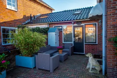 a dog sitting on a brick patio in front of a house at De Lijsterhof in Zandvoort