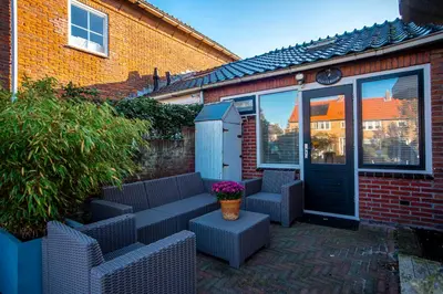 a patio with two chairs and a door with a pot of flowers at De Lijsterhof in Zandvoort