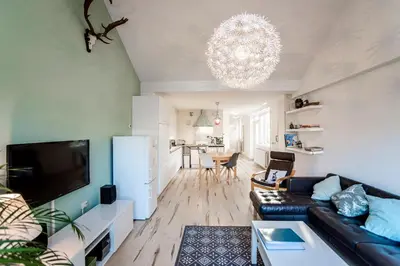 a living room with a black leather couch and a television at De Lijsterhof in Zandvoort