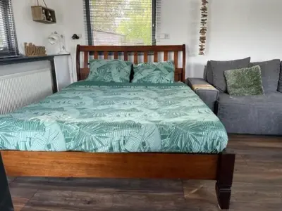 a bedroom with a wooden bed and a couch at Aangenaam op de Rijn, woonboot, inclusief privé sauna in Alphen aan den Rijn