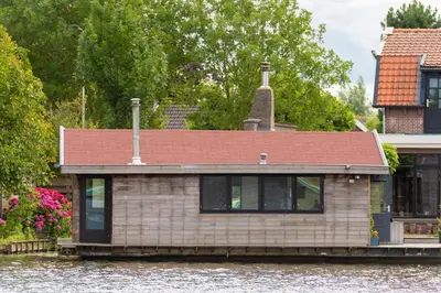 a house on a boat in a river at Aangenaam op de Rijn, woonboot, inclusief privé sauna in Alphen aan den Rijn