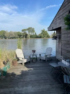 two chairs and a table on a dock next to a lake at Aangenaam op de Rijn, woonboot, inclusief privé sauna in Alphen aan den Rijn