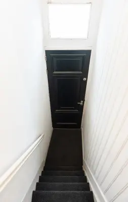 a stairway with a black door and a window at Canal View Apartment in Amsterdam