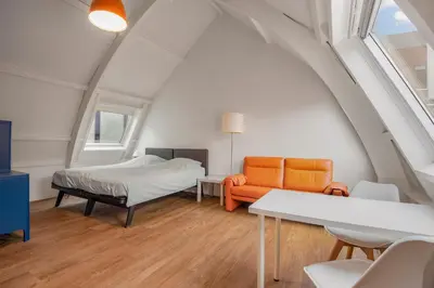an attic room with a bed and a couch at Five Churches View apartments in Haarlem