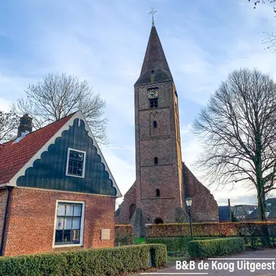 a church with a tower with a clock on it at Chalet - B&B de Koog in Uitgeest