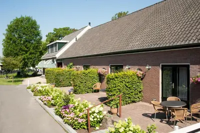 a building with a patio with tables and chairs and flowers at Christinahoeve Logies Oude Deel in Boskoop