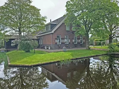 a house with its reflection in the water at Christinahoeve Logies Oude Deel in Boskoop