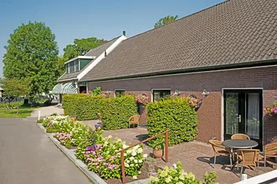 a brick building with a table and chairs and flowers at Christinahoeve Oude Deel #4 in Boskoop