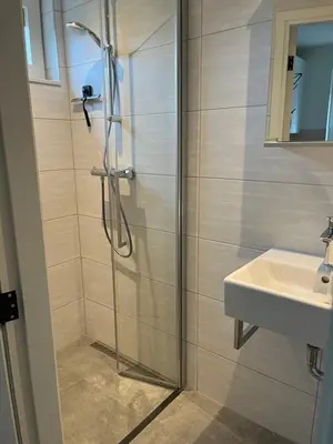 a shower with a glass door next to a sink at Christinahoeve Hooiberg #5 in Boskoop