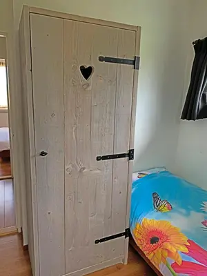 a bedroom with a wooden cabinet next to a bed at Christinahoeve Hooiberg #5 in Boskoop