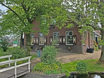 a brick house with a white fence in front of it at Christinahoeve Hooiberg #5 in Boskoop
