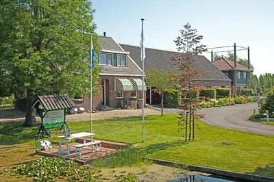 a house with a bench and flags in a yard at Christinahoeve Hooiberg #6 in Boskoop