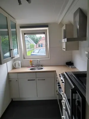 a small kitchen with a sink and a window at Lovely Bungalow 8p close to beach and Amsterdam in Opmeer