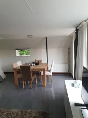a dining room with a wooden table and chairs at Lovely Bungalow 8p close to beach and Amsterdam in Opmeer