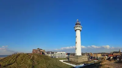 a lighthouse on top of a hill next to the ocean at Lovely Bungalow 8p close to beach and Amsterdam in Opmeer