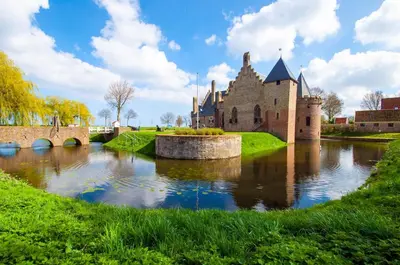 a castle with a river in front of it at Lovely Bungalow 8p close to beach and Amsterdam in Opmeer