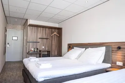 a bedroom with two beds with white sheets at Harbour Hotel IJmuiden in IJmuiden